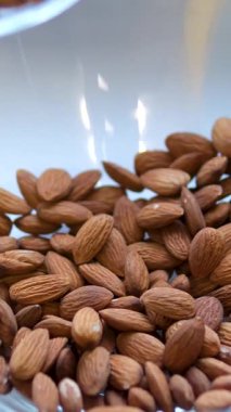 Badem unu, arka planda badem fıstığı olan cam bir kaseye dökülür. Yüksek kalite 4k görüntü