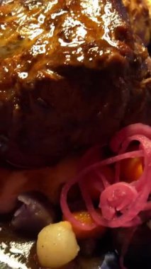 Etin üzerine kaşık sosu dök. Pişmiş kuzu budu. Kuzu etine koyu kırmızı sos ve salata. Şarabı ve yemek programı olan şefler masası. . 