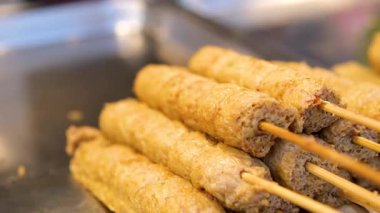 Lezzetli ızgara et şiş yakın çekim canlı yeşil bir yaprak üzerinde düzenlenmiş, yanında küçük bir kase renkli çeşni. Yüksek kalite 4k görüntü