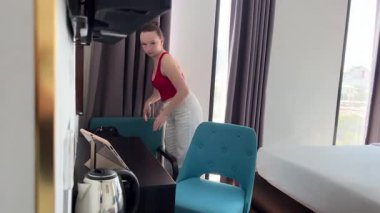 Kız, yeni otel kadınının tatil için gümüş bir bavul hazırlamasıyla mutlu bir şekilde yatağa düşüyor. Yakınlarda akıllı telefonu ve pembe güneş gözlüğü var. Seyahat hazırlıkları, yavaş çekim..