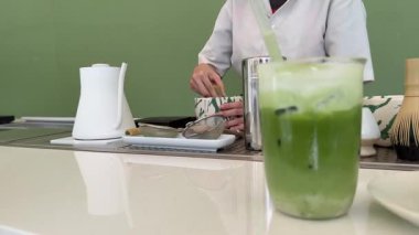 Yeşil kibrit çay tozu cam bardağa düşer. Geleneksel Japon içkisi. Yeşil çay yapıyorum. Suyu kibrit tozu ile karıştırıyorum. Sağlıklı içecek..