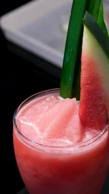 Bahçe düzeninde narenciye ve karpuz süsleriyle yaz içecekleri, bardakların yanında hasır şapka. Tropikal, açık hava rahatlaması ve sağlıklı içecek kavramları için mükemmel. Yüksek kalite 4k