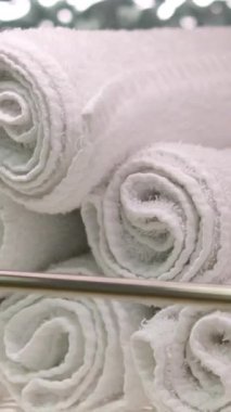Gri arka planda beyaz masanın üzerinde duran birkaç beyaz katlanmış havlunun 4k stok video görüntüsü. Kadın üç pamuk havluyu istifliyor. Yüksek kalite 4k