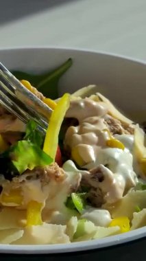 Papyonlu makarna salatası ve konserve ton balığı, havuç, soğan, mısır, domates, bezelye ve beyaz tabakta mayonez sosu. Yüksek kalite 4k görüntü