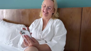 Mutlu, mutlu, mutlu, kaygısız, neşeli, beyaz, kadın, kanepede oturmuş, cep telefonuyla kayıyor, rahatlıyor, sohbet ediyor, sosyal medya uygulaması, alışveriş yapıyor..