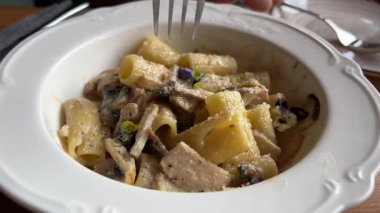 Makarnayı mantarlı, krem soslu ve parmesan peynirli kapayın. Tabakta döner, çatallı makarna döner. Fettuccine makarna pişiriyorum. İtalyan mutfağı. Yemek arkaplanı. Yüksek kalite 4k görüntü