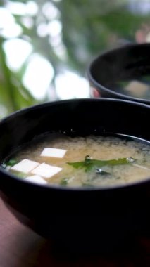 Miso çorbası servis kaşığıyla karıştırılırken yosun parçaları yüzeye çıkıyor. Kaşıkla miso çorbası karıştırmak. Yüksek kalite 4k görüntü