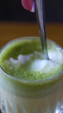 Buzlu ve tapyoka incili kibrit yeşil çay lattesi. Matcha latte pipetle karıştırılıyor. Bir kaşıkla karıştır