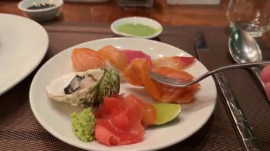 Sashimi tabağı çatalı kadın eli ve somon balığı sashimi. Japon restoranının terasında somonla suşi yiyen bir kız. Yüksek kalite 4k görüntü