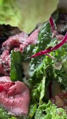 Sağlıklı beslenme konsepti. Masadaki kadın akşam yemeği için sağlıklı sebze salatası hazırlıyor, kadın spatulayla malzemeleri karıştırıyor ve tabağa porsiyon koyuyor. Salatayı tabağa koy.