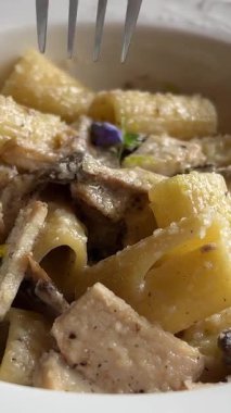 Makarnayı mantarlı, krem soslu ve parmesan peynirli kapayın. Tabakta döner, çatallı makarna döner. Fettuccine makarna pişiriyorum. İtalyan mutfağı. Yemek arkaplanı. Yüksek kalite 4k görüntü