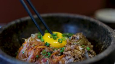 Biftek ve sosla birlikte pirinç üzerine serpiştirilmiş sahanda yumurta sarısı..