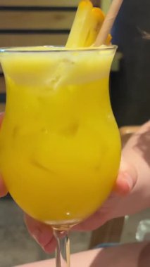 Çikolatalı milkshake buzunu kamışla karıştıran kadın elleri. Güneşli tropikal kafede çikolatalı milkshake içen genç bir kadın. İçeride tropik kokteyl.