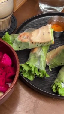 İki kişilik vejetaryen yemeği. Soslu, yeşil sağlıklı meyve püresi ve ahşap tabakta servis edilen organik rulo. Yüksek kalite 4k görüntü