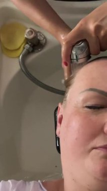 Kuaför boyamadan önce kadınların saçlarını yıkar. Kuaför esmer saçlarını yıkıyor. Siyah saçlı. Yüksek kalite 4k görüntü