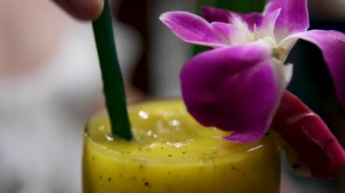 Sağlıklı tatlılar konsepti. Tahta bir masada servis edilen bardaktaki tropik chia pudingi. Arkada çiçekler var. Yüksek kalite 4k görüntü