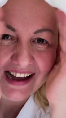 İki taraflı aynanın önünde çarşaf maskesi takan bir kadın. Beyaz bornozlu güzel bir kız elinde kahve ya da çay bardağıyla oturuyor. Rahatla ve rahatla. Önünde bir sürü kozmetik var. .