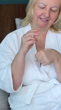 İki taraflı aynanın önünde çarşaf maskesi takan bir kadın. Beyaz bornozlu güzel bir kız elinde kahve ya da çay bardağıyla oturuyor. Rahatla ve rahatla. Önünde bir sürü kozmetik var. .