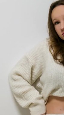 Beyaz duvar kenarına sıkışmış kazak giymiş karın kaslarını gösteren genç kız senin gibi ergenlik çağında kilo vermeye çalışıyor. Yüksek kalite 4k görüntü