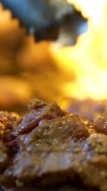 Şefler tavada kavurucu ateşle erişte pişiriyor. Bir aşçının yakın çekimi Çin yemeği hazırlarken malzemeleri kızartma tavasına atar. Yavaş çekim 4K videosu. Yüksek kalite 4k görüntü