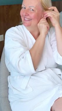 İki taraflı aynanın önünde çarşaf maskesi takan bir kadın. Beyaz bornozlu güzel bir kız elinde kahve ya da çay bardağıyla oturuyor. Rahatla ve rahatla. Önünde bir sürü kozmetik var. .