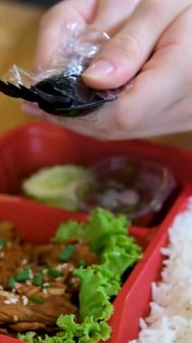 Kırmızı bir konteynırda pirinç, Asya mutfağında tek kullanımlık siyah plastik sofra takımı, çatal, bıçak, aç, yemeye başla, teslimat. Yüksek kalite 4k görüntü