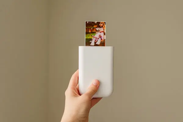 Kadın taşınabilir bir yazıcıya fotoğraf yazdırıyor. 
