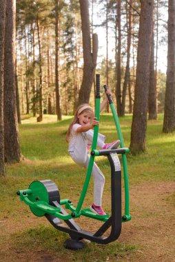 Genç kız oyun parkında egzersiz yapıyor.