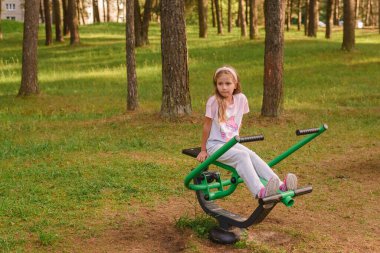 Kız parktaki egzersiz aletleri üzerinde çalışıyor.