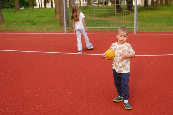 Genç çocuk oyun alanında basketbol oynuyor.