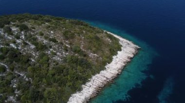 Kıyıdaki mavi okyanus ve yeşil orman. Yükseklerden deniz. Gök mavisi. Scooter okyanusta. Suyun üzerinden uçmak. Deniz kıyısındaki yol. Saf doğa ve su. Kumsalda beyaz kum. 