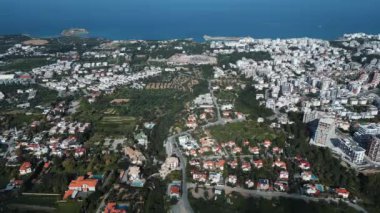 Bir sahil kasabasının üzerinde uçuyor. Okyanustaki şehir. Kuzey Kıbrıs. Manzara ve deniz. Yüksek kalite 4k görüntü