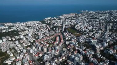 Bir sahil kasabasının üzerinde uçuyor. Okyanustaki şehir. Kuzey Kıbrıs. Manzara ve deniz. Yüksek kalite 4k görüntü