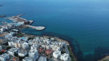 Bir sahil kasabasının üzerinde uçuyor. Okyanustaki şehir. Kuzey Kıbrıs. Manzara ve deniz. Yüksek kalite 4k görüntü