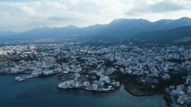 Bir deniz kenti üzerinde bulutlar ve güneş ışınları arasında uçuyor. Güneş ışığındaki dağlar. Yüksek kalite 4k görüntü