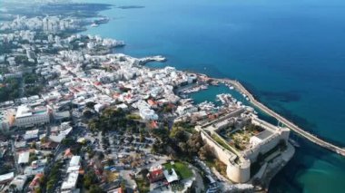 Kıbrıs 'ta bir sahil kasabasının üzerinde uçuyor. Bir liman kasabası. Dağlardaki evler. Limanda yatlar. Bulutların arasından geçen güneş ışınları. Yüksek kalite 4k görüntü