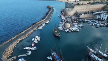 Kıbrıs 'ta bir sahil kasabasının üzerinde uçuyor. Bir liman kasabası. Dağlardaki evler. Limanda yatlar. Bulutların arasından geçen güneş ışınları. Yüksek kalite 4k görüntü