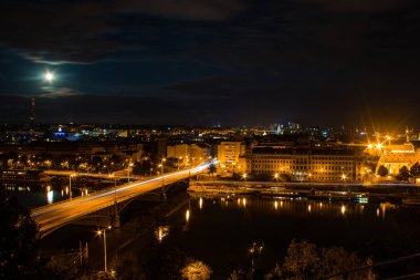 Çek Cumhuriyeti, Letna 'dan Prag' ın gece manzarası aydınlık ufuk çizgisinin üzerindeki dolunayı Vltava Nehri 'nde yansıyan yansımalarla gösteriyor..