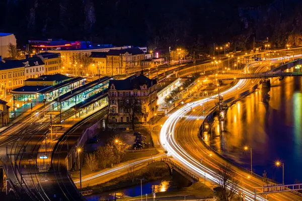 Çek Cumhuriyeti 'nin Usti nad Labem kentinin gece manzarası. Elbe Nehri' nin kıyısındaki aydınlık tren istasyonları ve arabalardan oluşan hafif patikaları var..