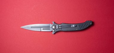 Kırmızı arka planda siyah katlanır bıçak.