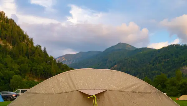 camping and tent with drops of night rain at dawn against the backdrop of the Austrian mountains