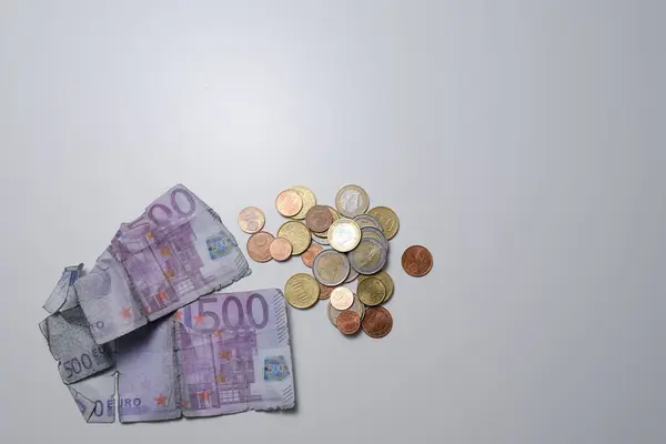 Yıpranmış euro banknotları ve bozuk paralar beyaz bir masanın üzerinde