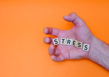 STRESS kelimesi, avucunun içindeki ahşap harflerden felçli parmaklarla yayılmıştır.