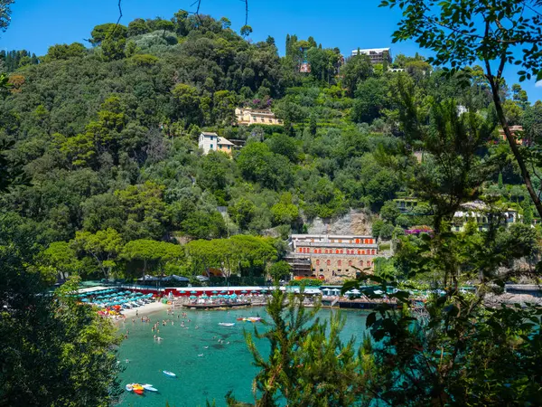 İtalya 'da Akdeniz kıyıları, Portofino yeşilliğe batmış bir dağın zeminine karşı, tatilcilerin olduğu güzel bir plaj.