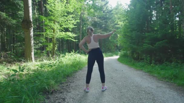 这个女孩在森林里跑之前正在热身 健康的小女孩正在室外热身 — 图库视频影像