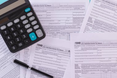 Tax fill concept, pen and calculator  with 1040 U.S. form backgound