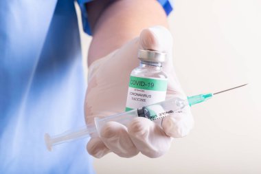 Doktorlar ellerinde bir şişe kovid-19 Coronavirus ve şırınga tutuyorlar.