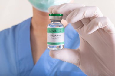 Doktorlar elinde bir şişe covid-19 Coronavirus tutuyor.