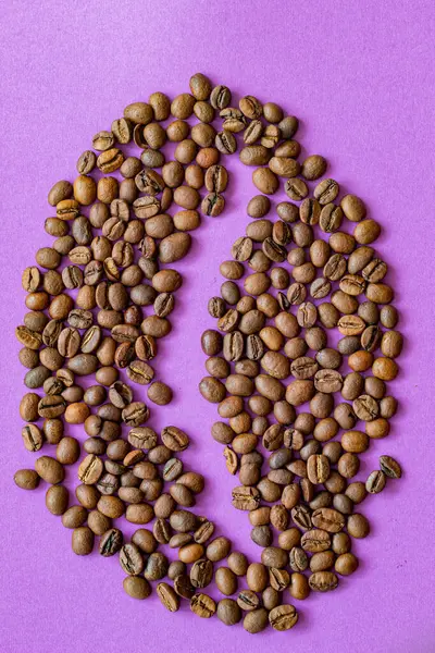 Mor fonda kahve çekirdekleri. Kahve çekirdekleri kahve çekirdeği şeklinde serilmiş. Mor arkaplanda bir yazı yeri var.