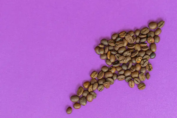 coffee beans laid out in the form of an arrow on a purple background, rising price of coffee, growing consumption,with a place for inscription